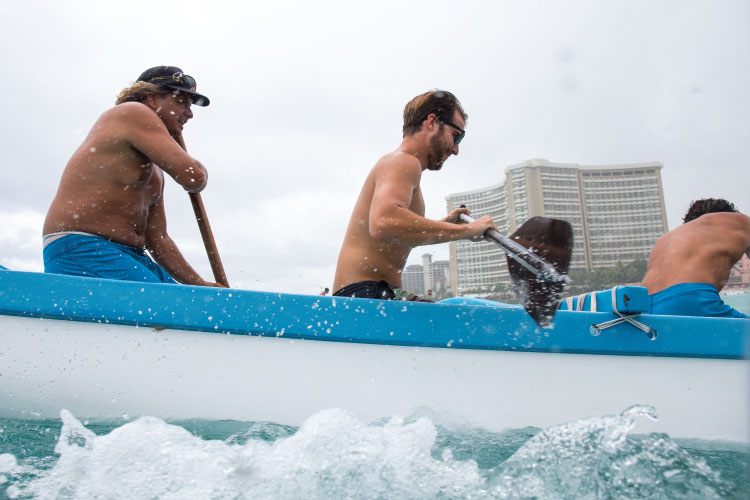 “This is just another day at the office,” said Zane Aikau (left) steering an outrigger canoe with writer Cash Lambert (middle). Photo: Heff
